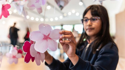 A child holding some petal art held from string